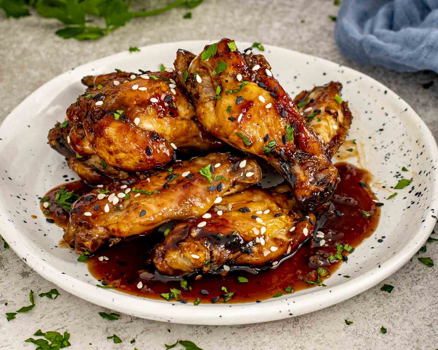 Golden baked honey garlic chicken wings served on a white plate with extra sauce pooling underneath.