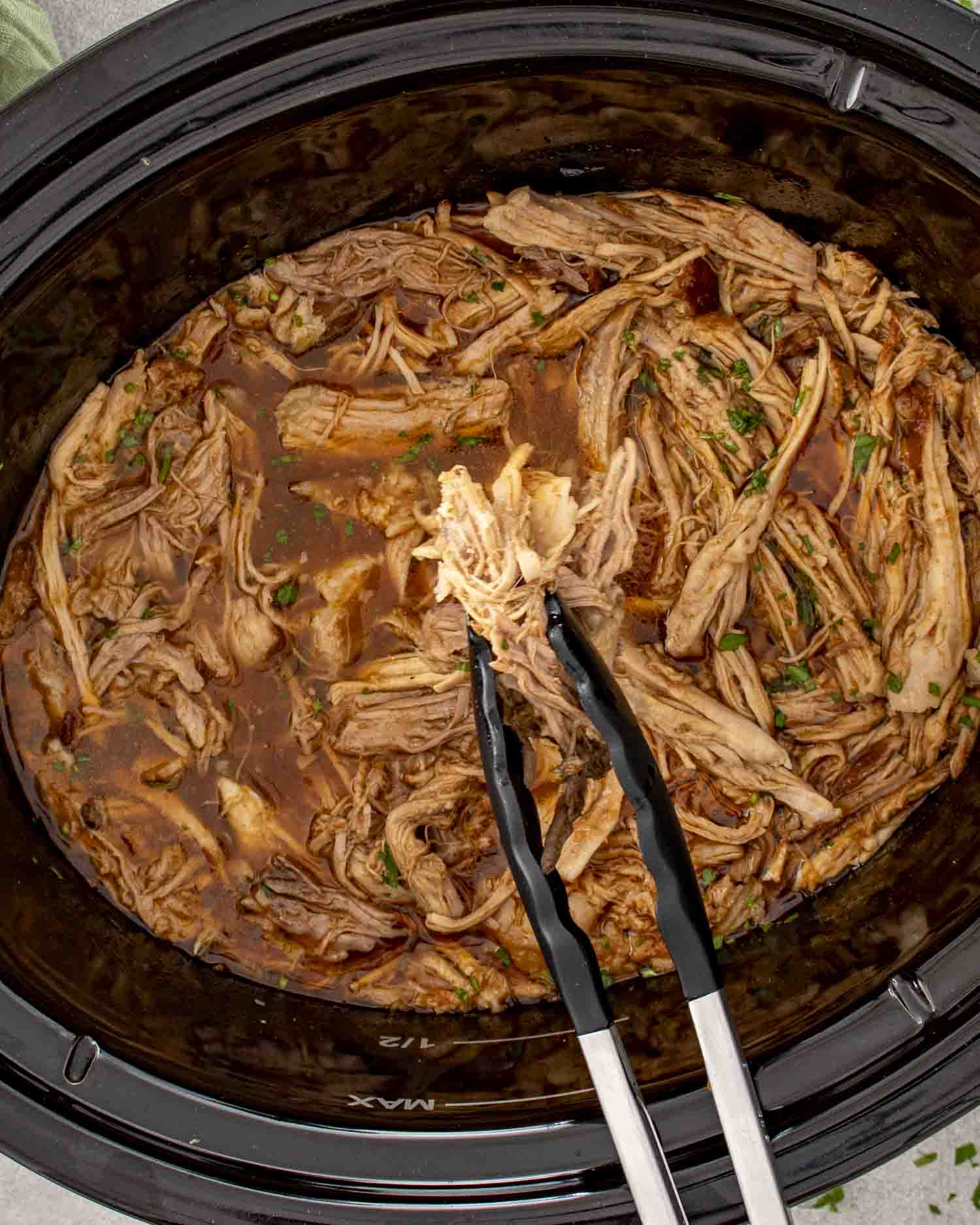 Tender BBQ pulled pork resting in slow cooker, fully shredded and coated in savory, smoky barbecue sauce.