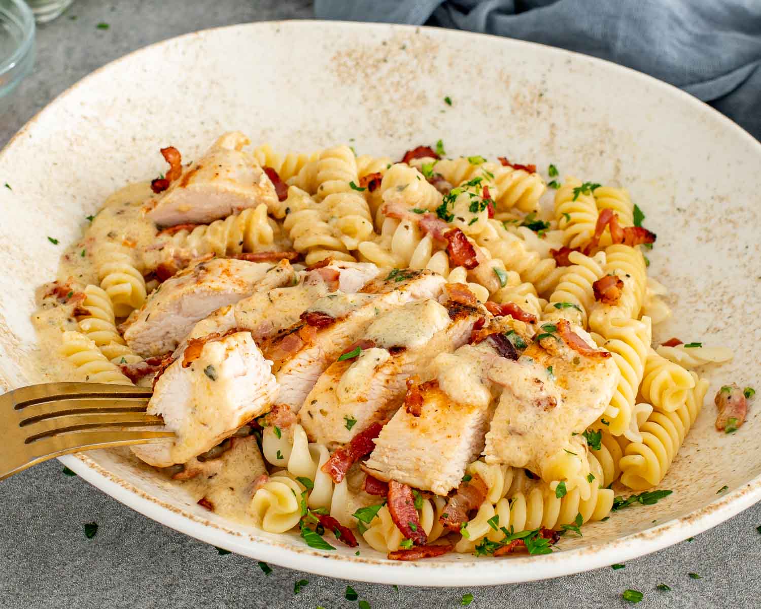 Close-up of creamy garlic parmesan chicken and pasta showing tender sliced chicken, crispy bacon, and thick creamy sauce.