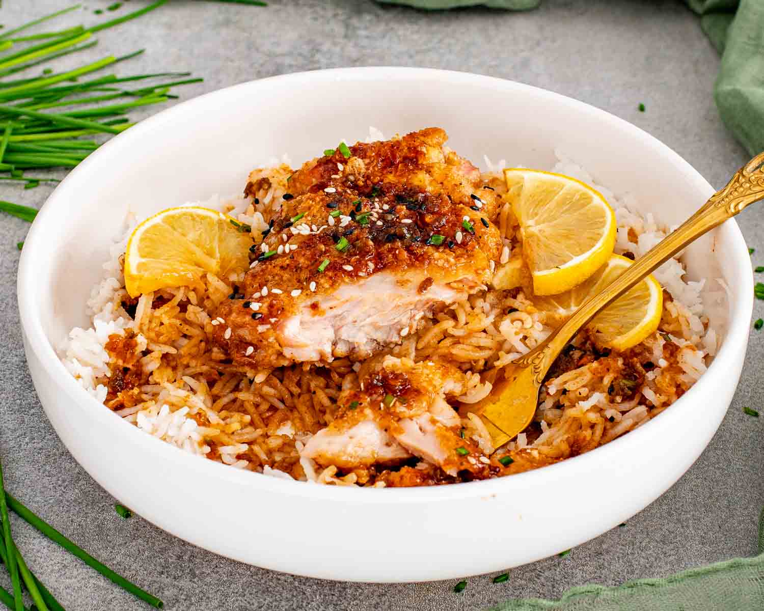 Sliced honey lemon garlic chicken over rice drizzled with sticky garlic lemon sauce and sesame seeds.