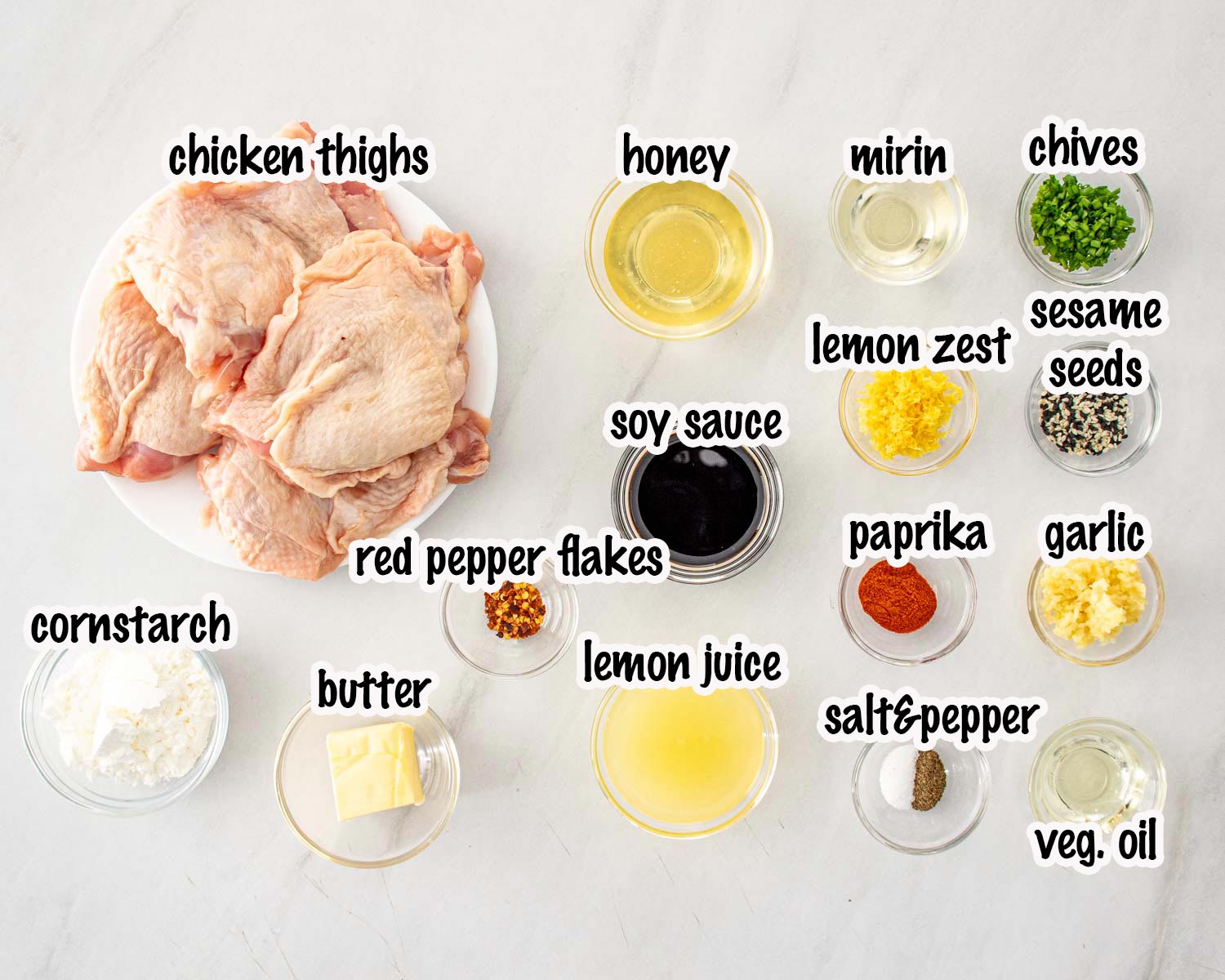 Ingredients for honey lemon garlic chicken including chicken thighs, honey, soy sauce, garlic, lemon juice, mirin, and sesame seeds.