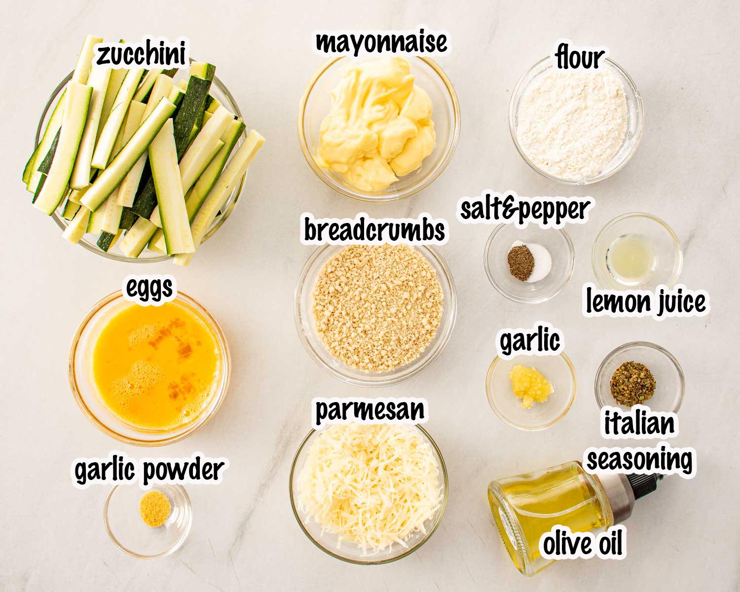 Ingredients for crispy zucchini fries including zucchini sticks, panko, Parmesan, eggs, flour, and garlic aioli components.
