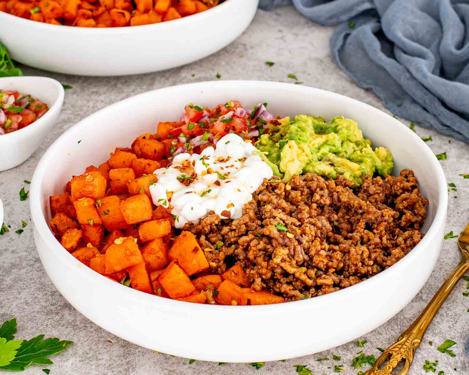 Hot honey taco beef bowl with roasted sweet potatoes, taco beef, avocado mash, tomato salsa, cottage cheese and chili flakes.