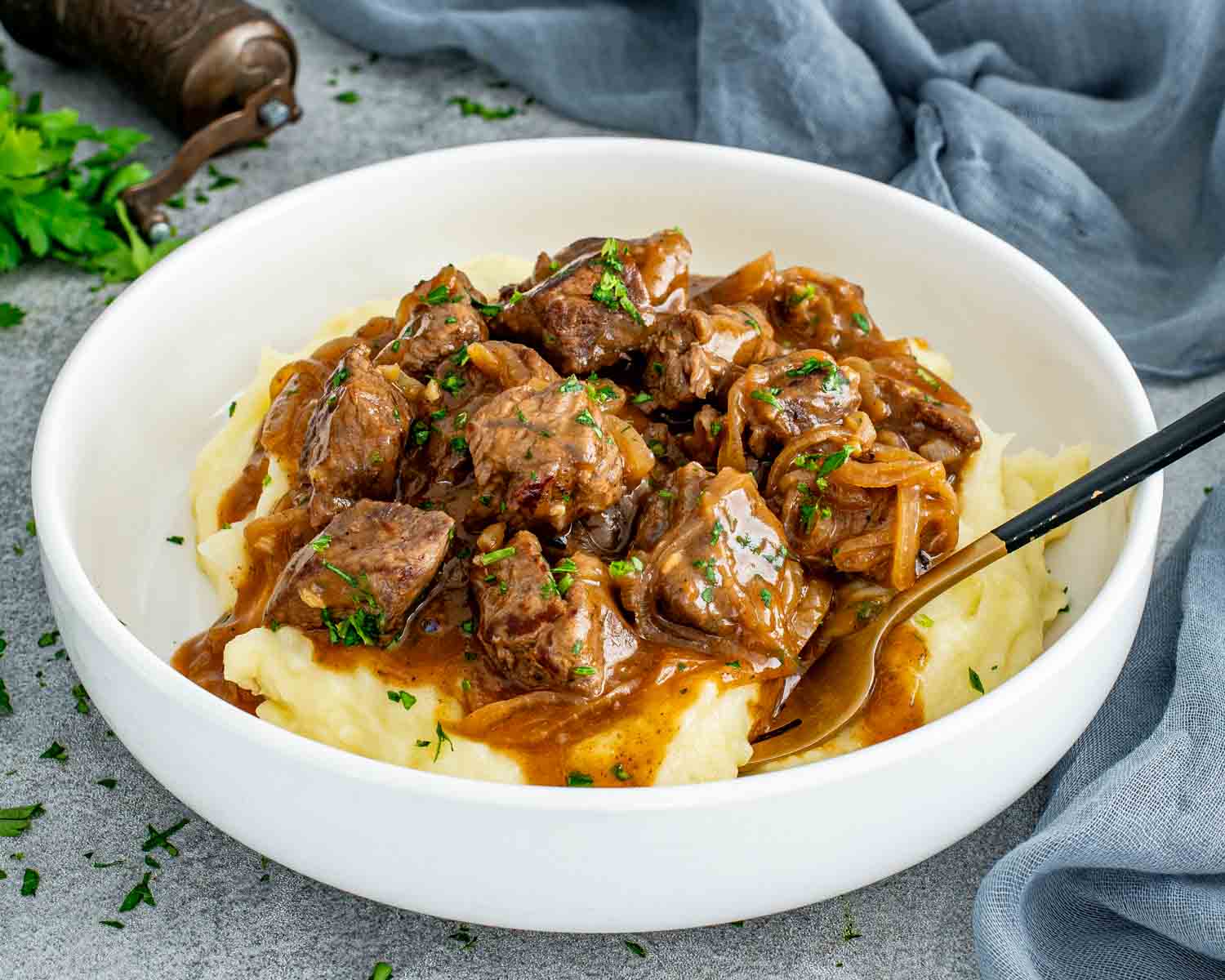 Beef and onion skillet served over creamy mashed potatoes with tender beef, rich gravy, and soft onions, finished with fresh herbs.