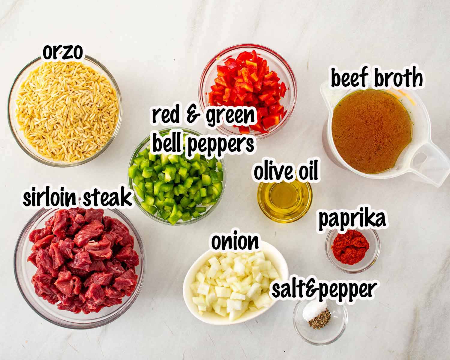 Raw ingredients for beef orzo including sirloin steak, orzo, beef broth, chopped peppers, onions, and spices in glass bowls.