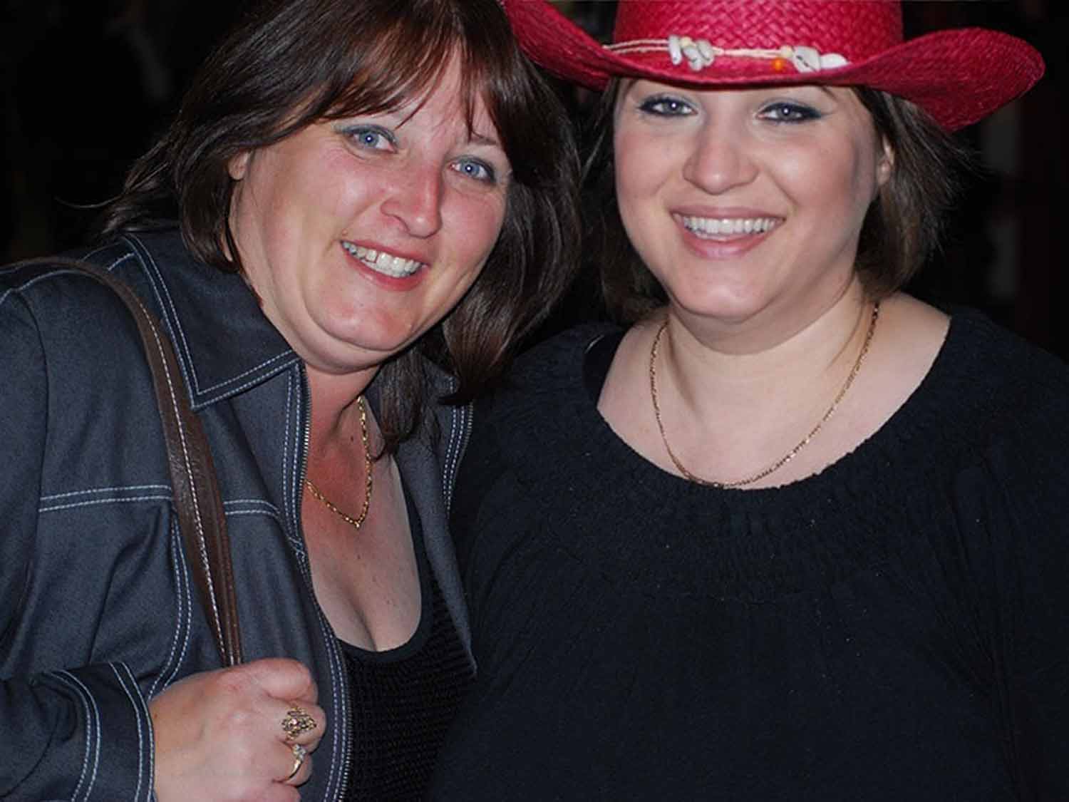 Jo and her sister smiling together at an event, Jo wearing a red cowboy hat and her sister in a denim jacket, both laughing.