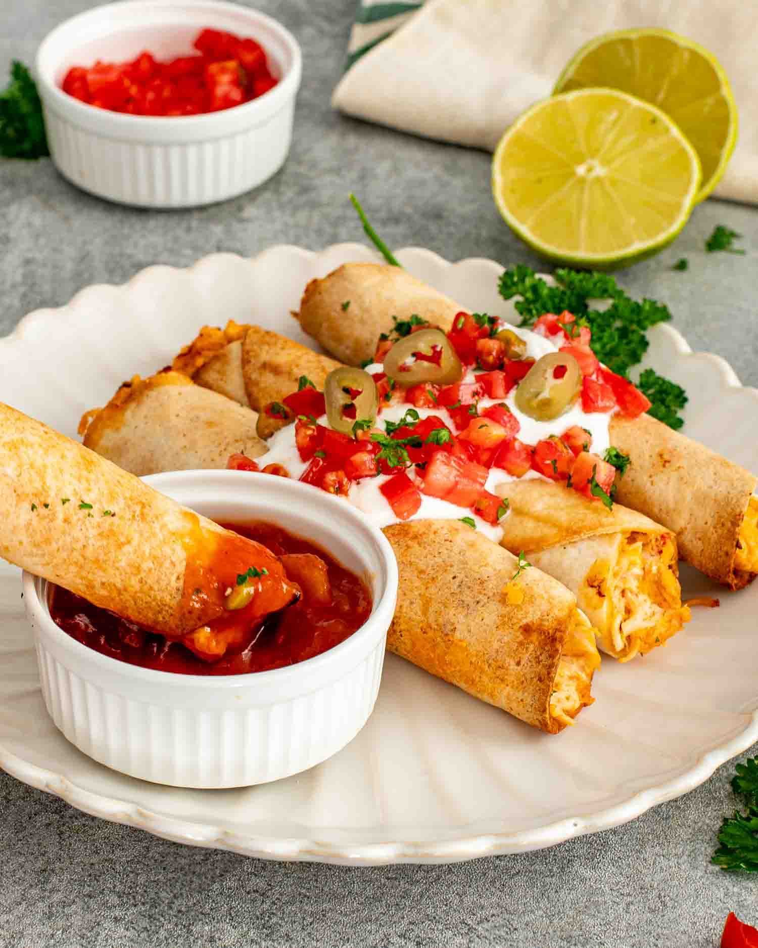 Chicken taquito dipped into chunky salsa with crispy tortillas, creamy filling, sour cream, pico de gallo, and fresh lime.