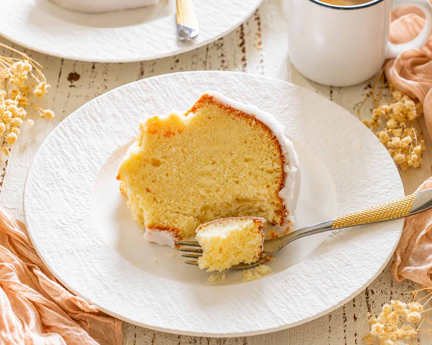 Moist slice of pineapple cream cheese pound cake with pineapple glaze, served with a forkful ready to enjoy.