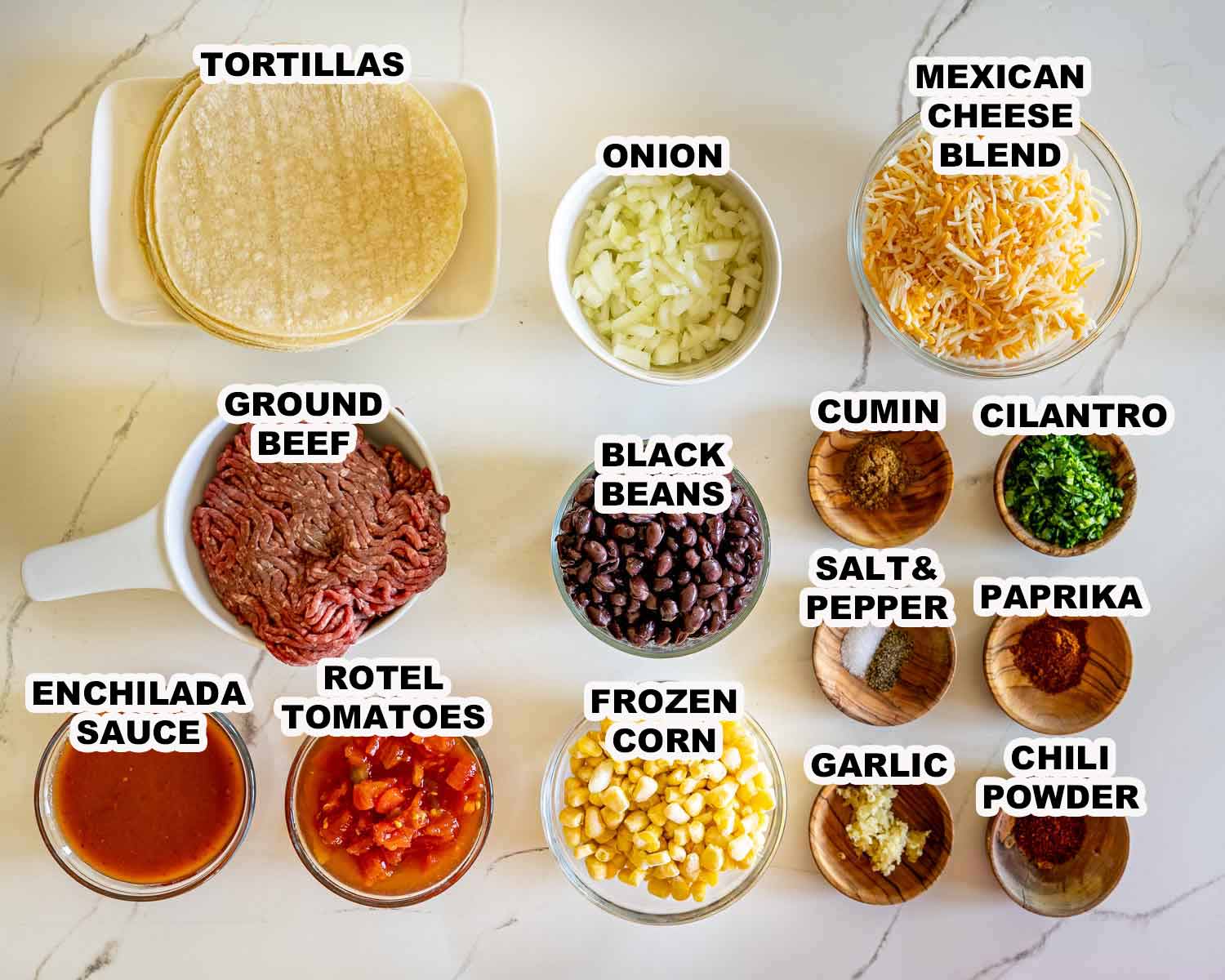 Labeled overhead display of tortillas, ground beef, cheese, beans, corn, vegetables, enchilada sauce, seasonings, garlic, and cilantro.