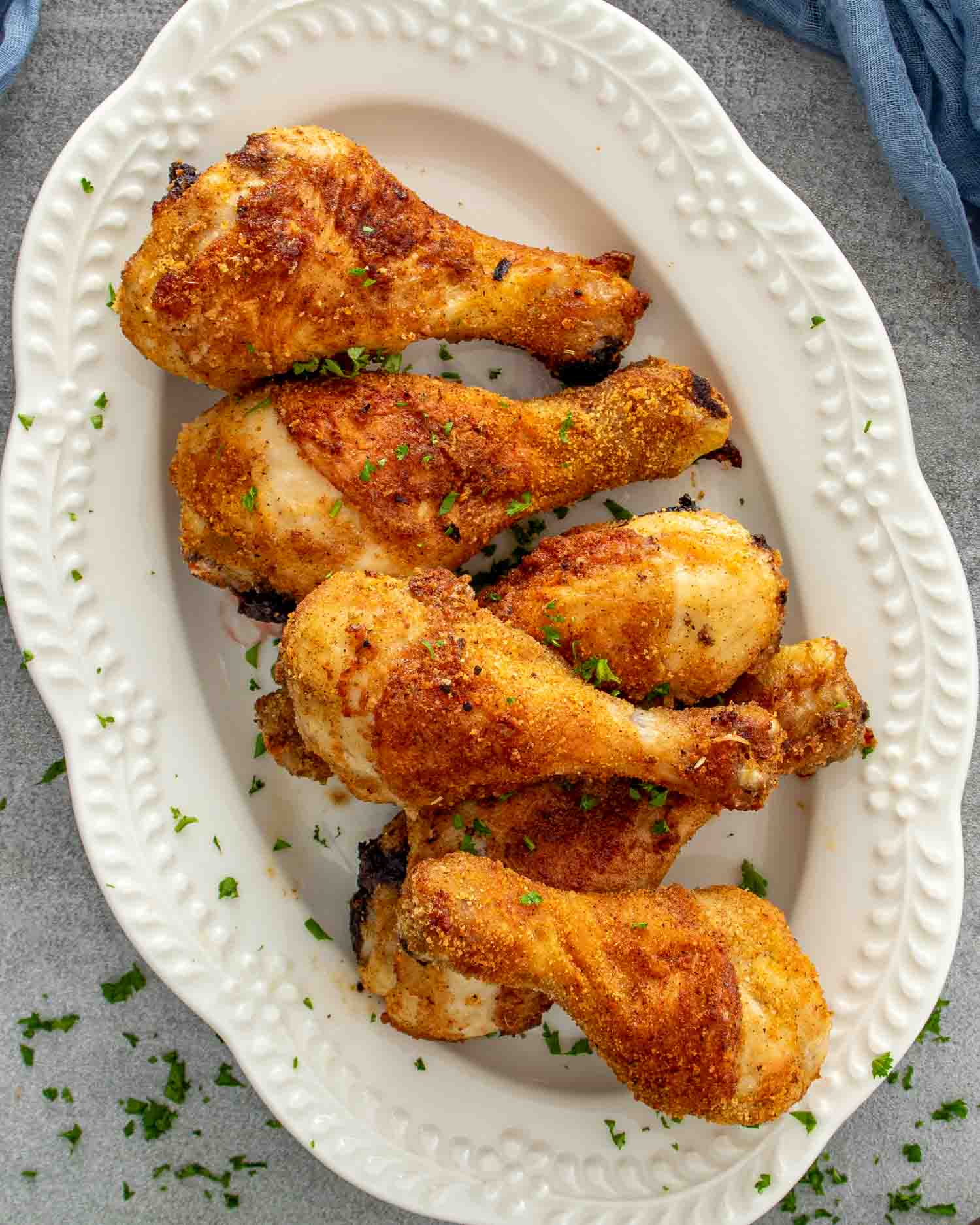 Close-up of crispy Air Fryer Shake-and-Bake Chicken drumsticks piled on a serving platter with golden, crunchy homemade breadcrumb coating.