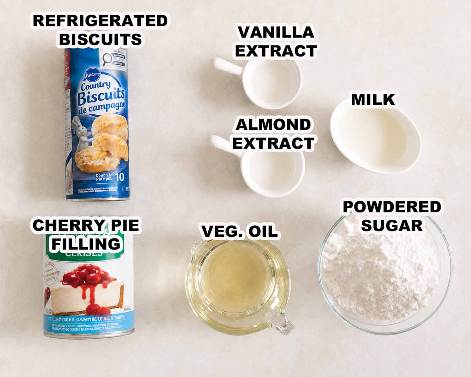 Labeled ingredients for cherry hand pie donuts, including biscuit dough, cherry filling, extracts, milk, oil, and powdered sugar.