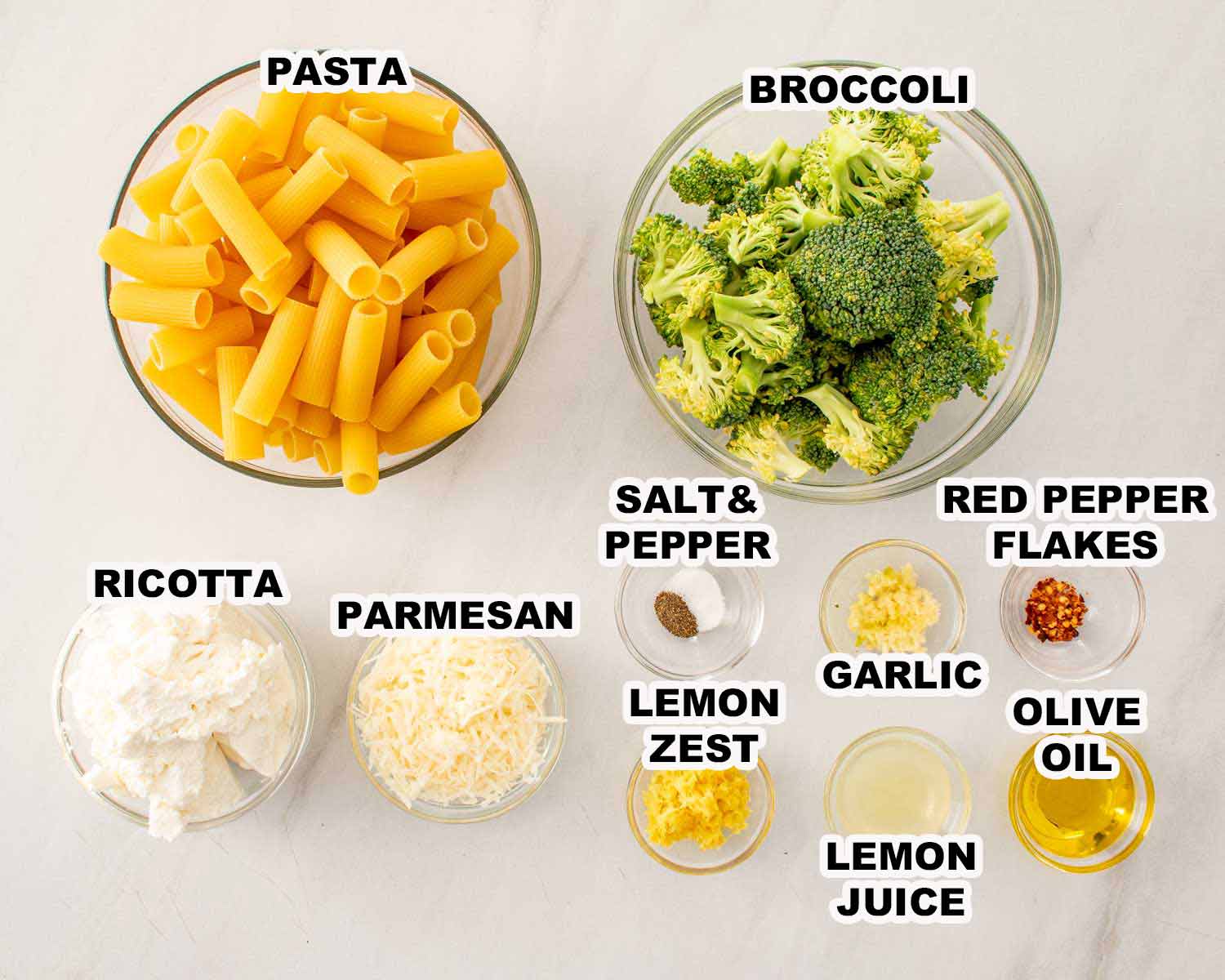 Labeled ingredients for lemon ricotta pasta include rigatoni, broccoli, ricotta, Parmesan, garlic, lemon, seasonings, and olive oil.