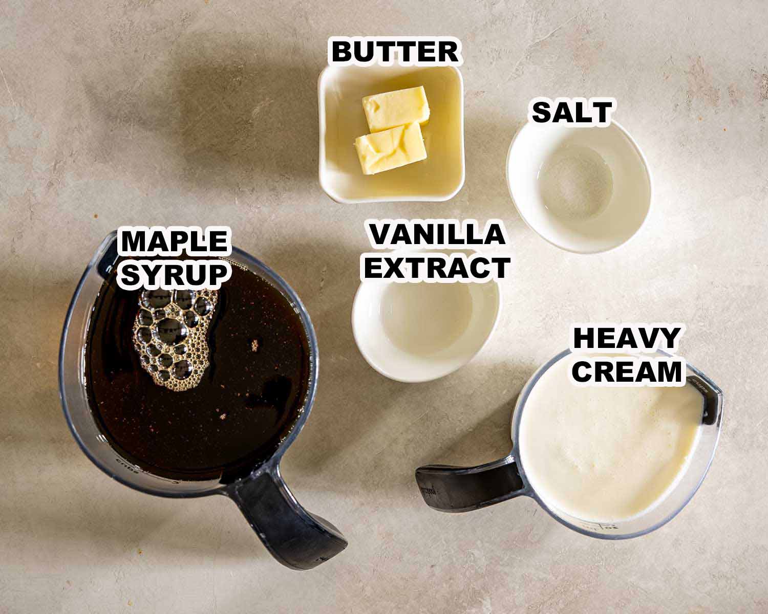 Labeled overhead display of maple fudge ingredients including maple syrup, heavy cream, butter, vanilla extract, and salt.