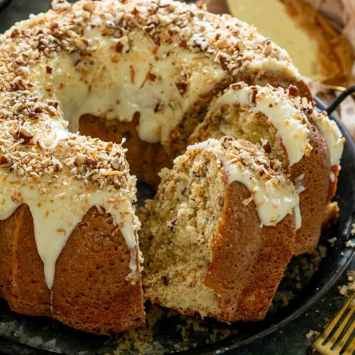 Close-up of toasted coconut Italian cream Bundt cake showing its moist interior, creamy glaze, toasted coconut, and chopped pecans.