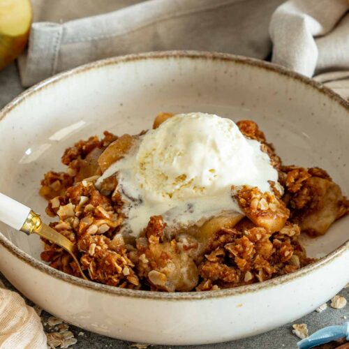 Warm apple crisp with tender cinnamon apples, crunchy oat topping, and a melting scoop of vanilla ice cream.
