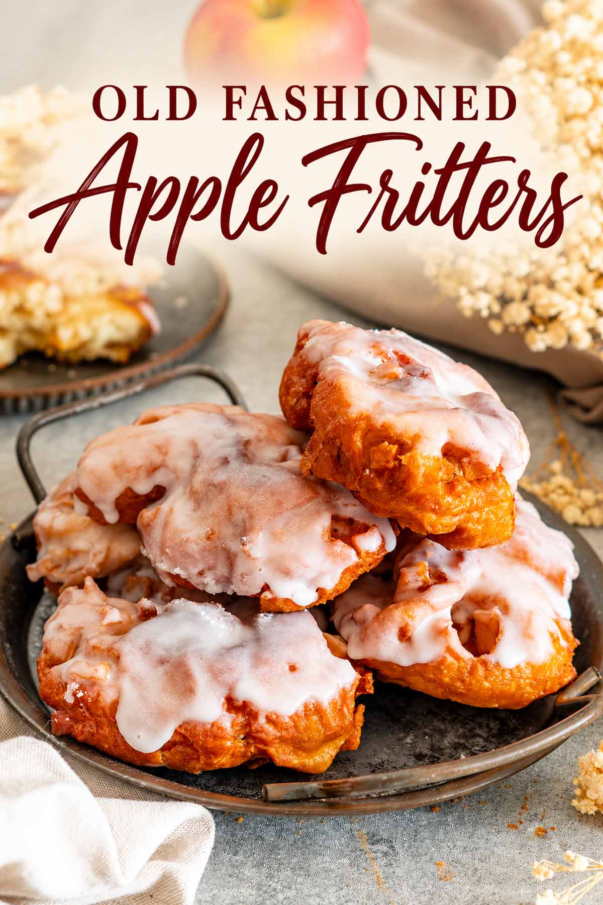 Pinterest graphic with stacked glazed apple fritters on a rustic tray and the title Old Fashioned Apple Fritters.