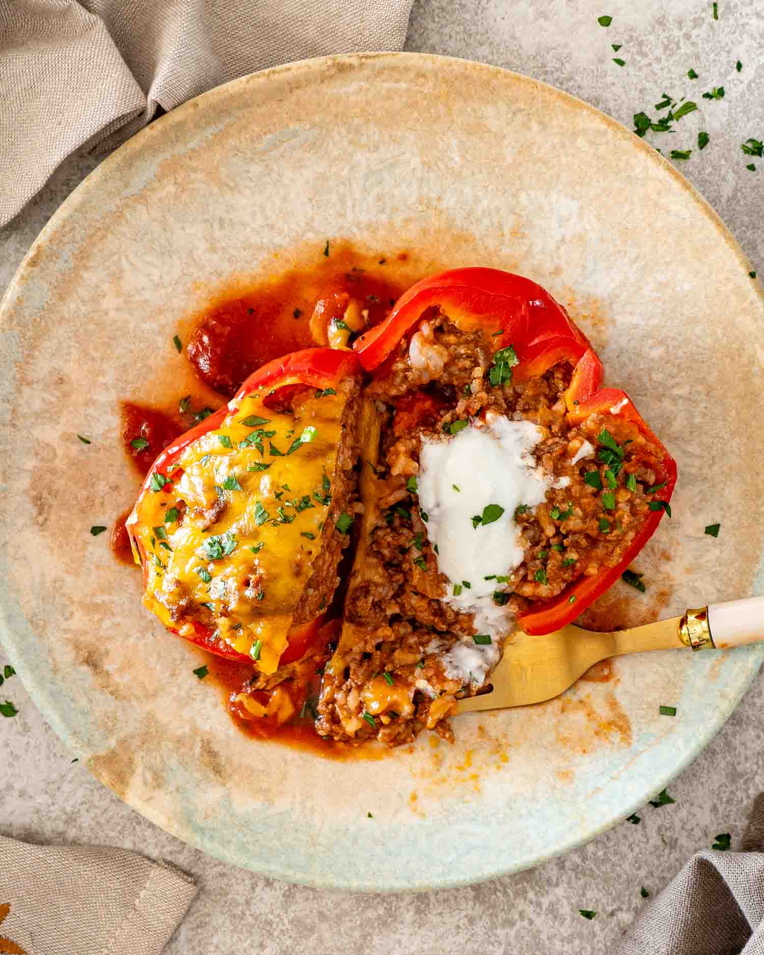 Stuffed red pepper cut open to reveal the seasoned ground beef and rice filling beneath melted cheddar.