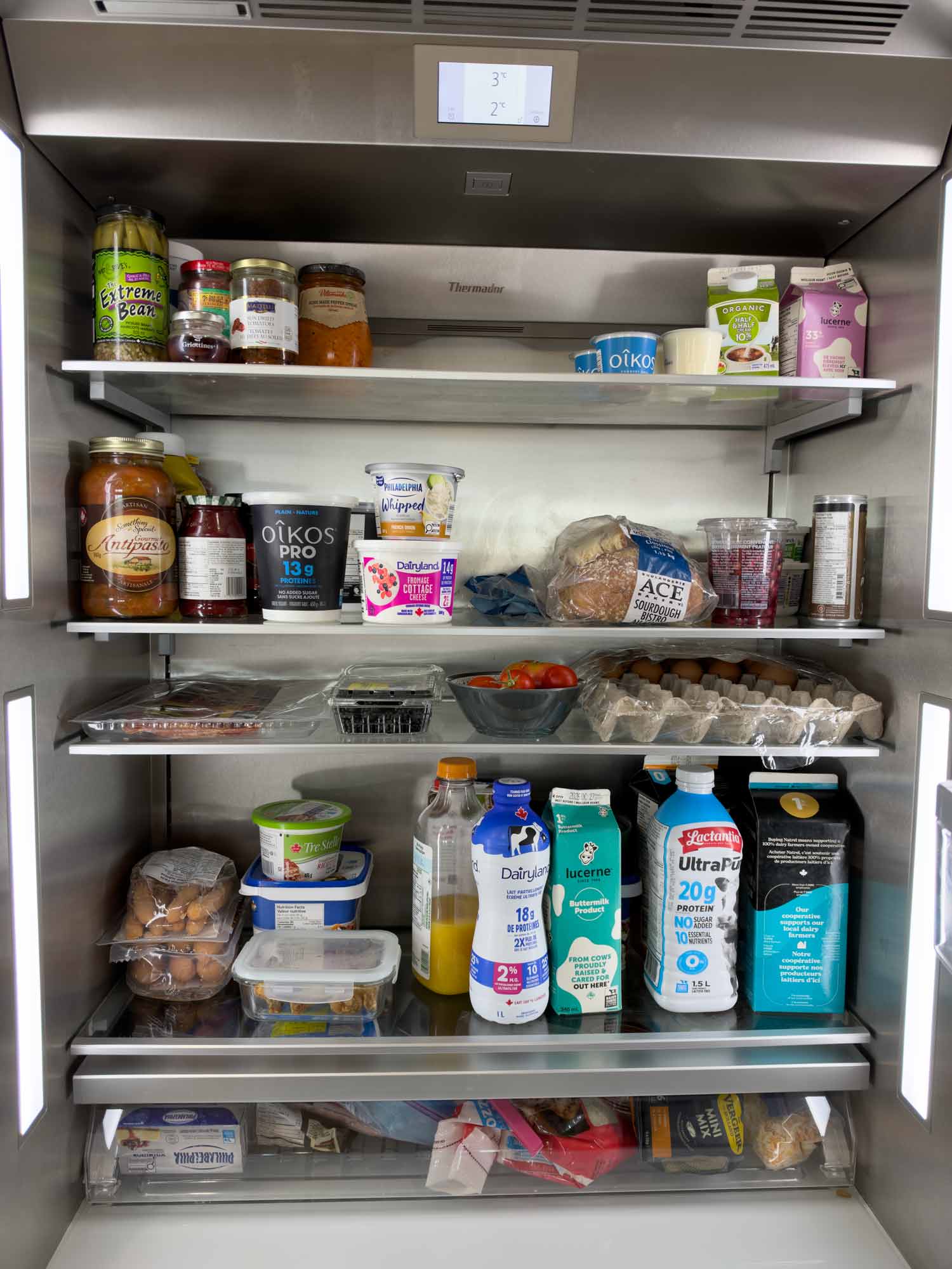 Inside Joanna's refrigerator stocked with high-protein dairy products, eggs, fresh berries, vegetables, sourdough bread, and everyday groceries.